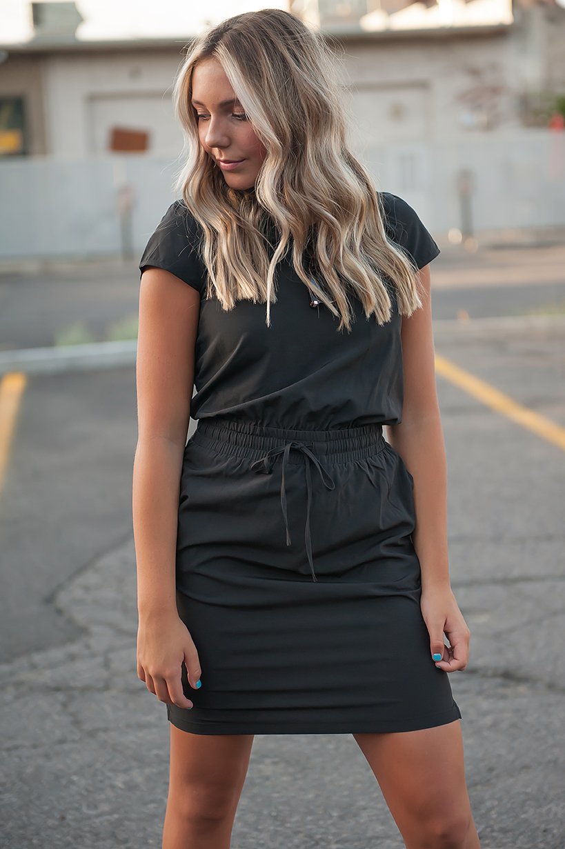 Model wearing black dress with drawstring waist and cap sleeves
