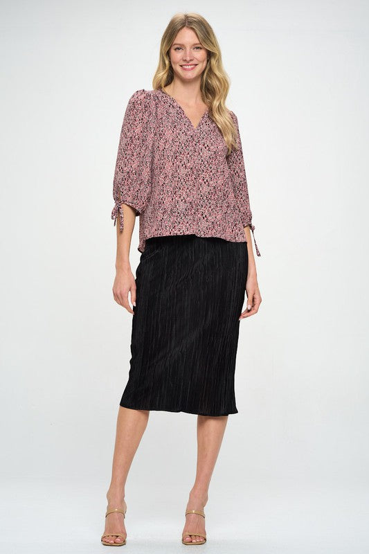 Knee-length plissé skirt paired with heels and blouse