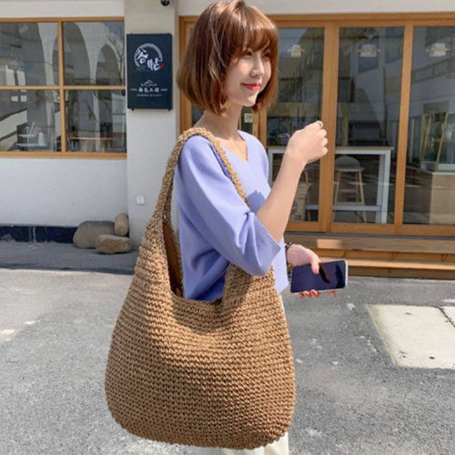 Woman holding boho straw tote at the beach