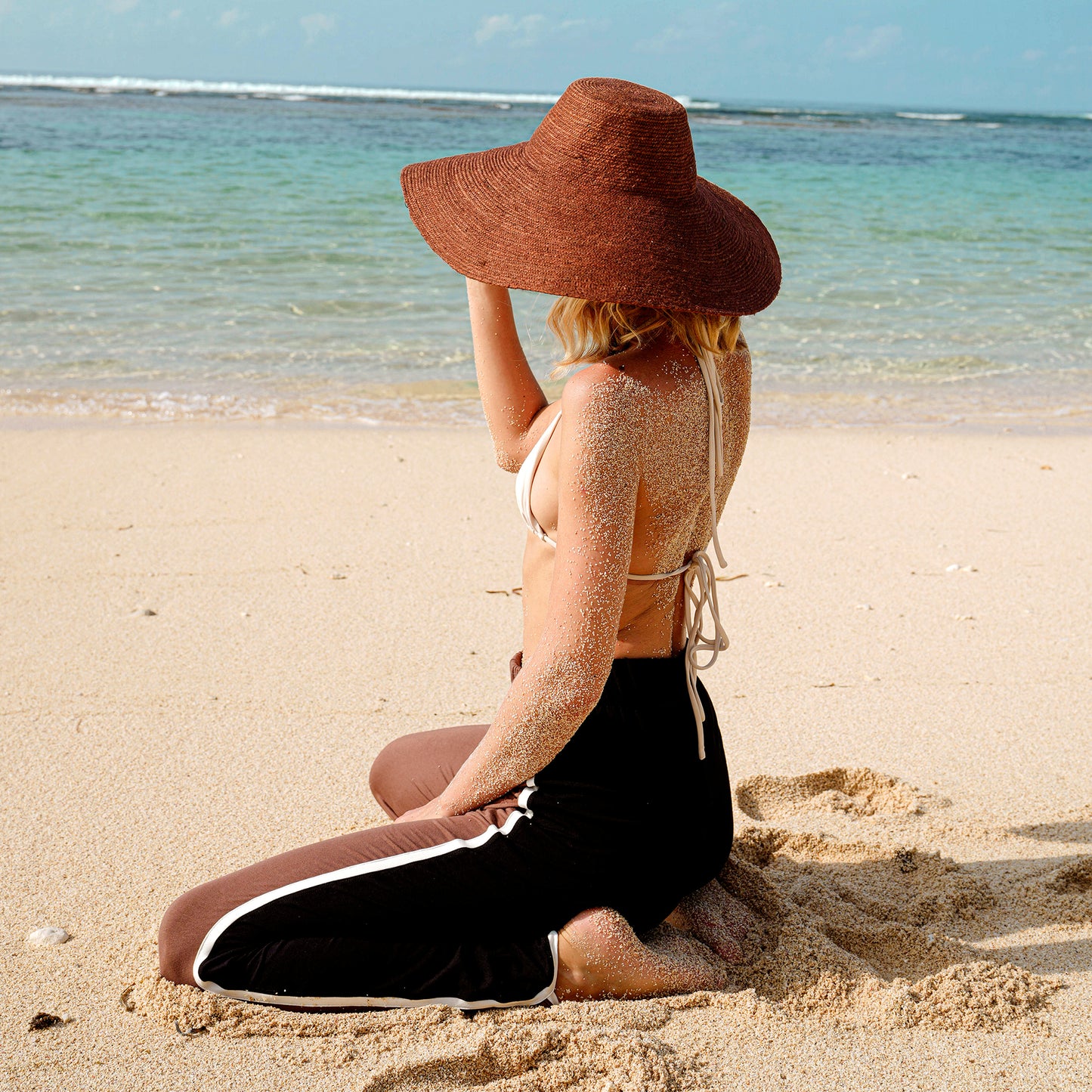 Woman wearing wide-brimmed burnt sienna jute hat on the beach