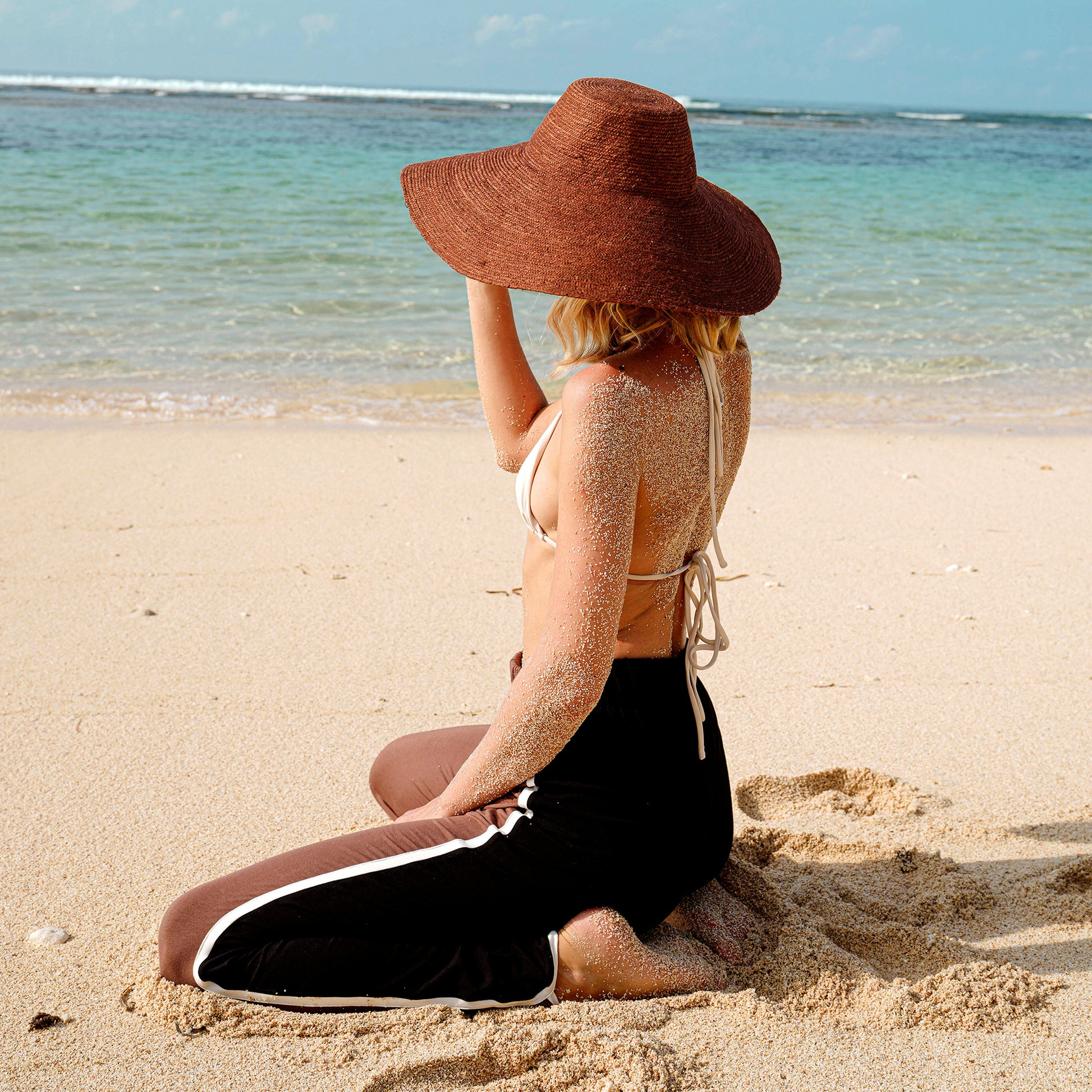 Woman wearing wide-brimmed burnt sienna jute hat on the beach