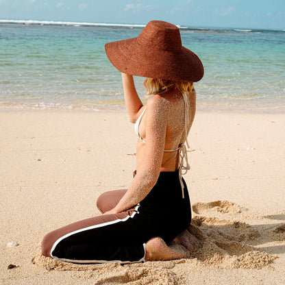 Woman wearing wide-brimmed burnt sienna jute hat on the beach